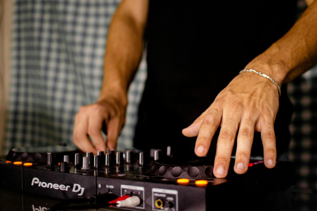 Close-up of a DJ mixing music on a Pioneer deck, focusing on hand movements.